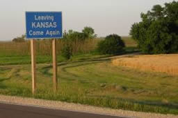road sign: Leaving Kansas Come Again
